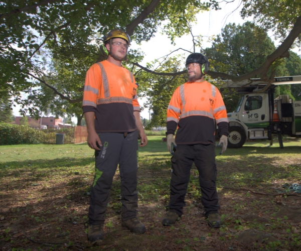 A photo of 2 ground crews of Higher Ground Tree Care under the shade of a tree in Edwardsburg, MI.