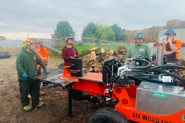 Team of Higher Ground Tree Care surrounding a new log splitter machine in Edwardsburg, MI.