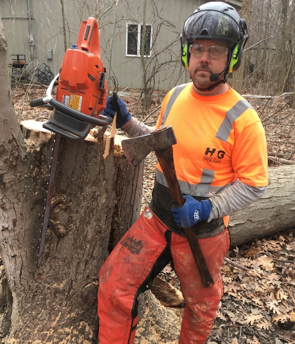 Higher Groung Tree Care arborist in close up photo with an axe and chainsaw after a tree removal on a residence in South Bend, Indiana.